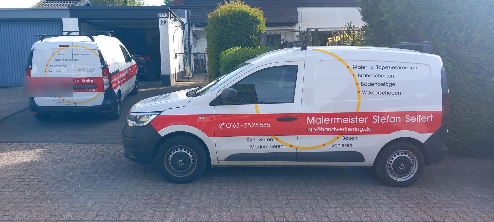 Zwei Firmenfahrzeuge in einer Einfahrt